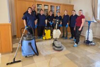 Schülergruppe posiert mit Reinigungsequipment auf Steinboden